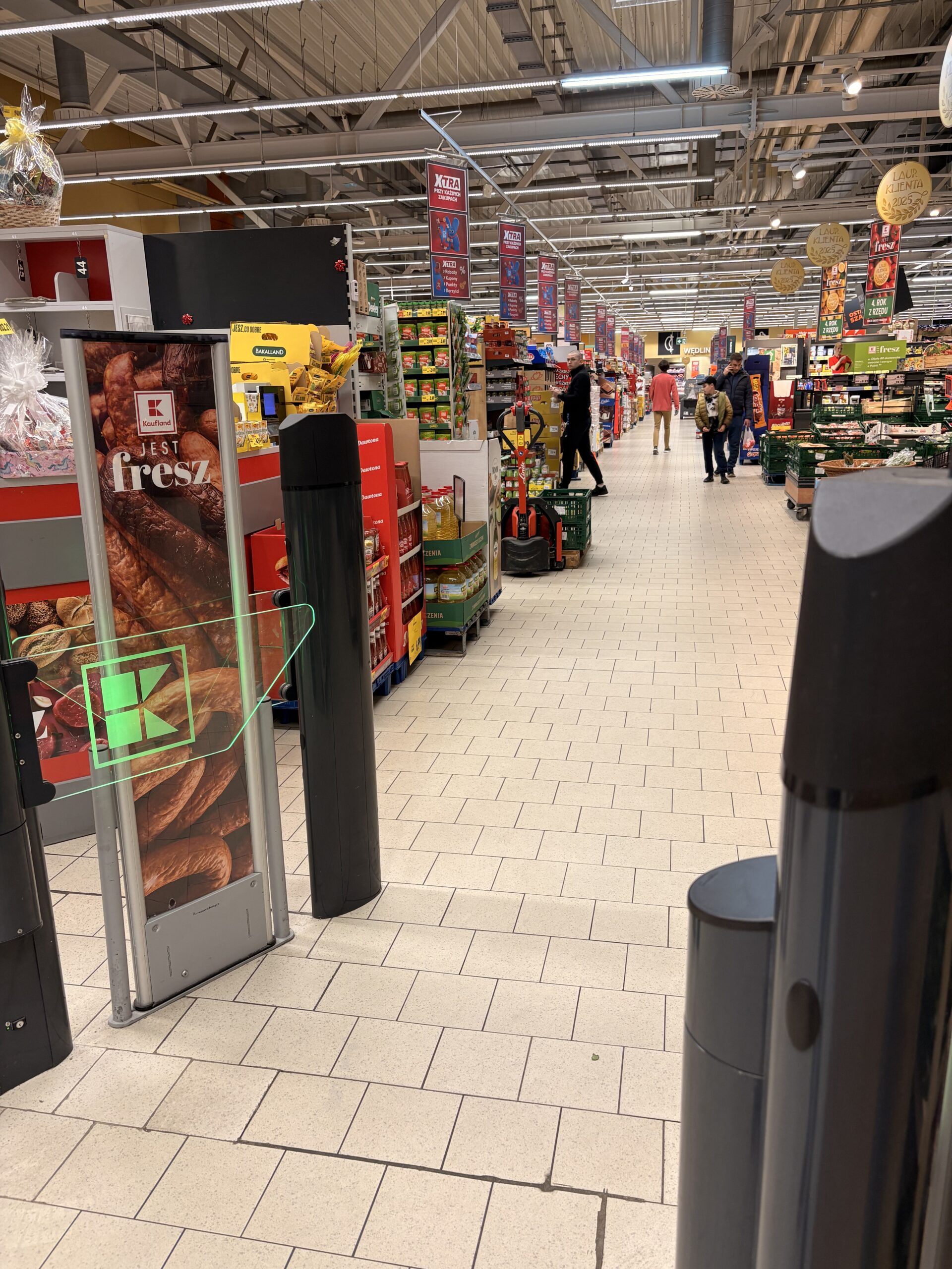 Display Heinza wciśnięty między kasy a palety — kontekst lokalizacji przy wejściu
