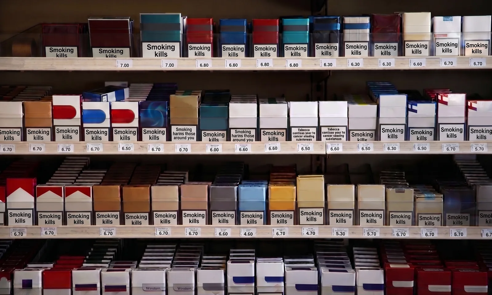 A cigarette display photographed head on, four shelves of packs with a printed price label under every row